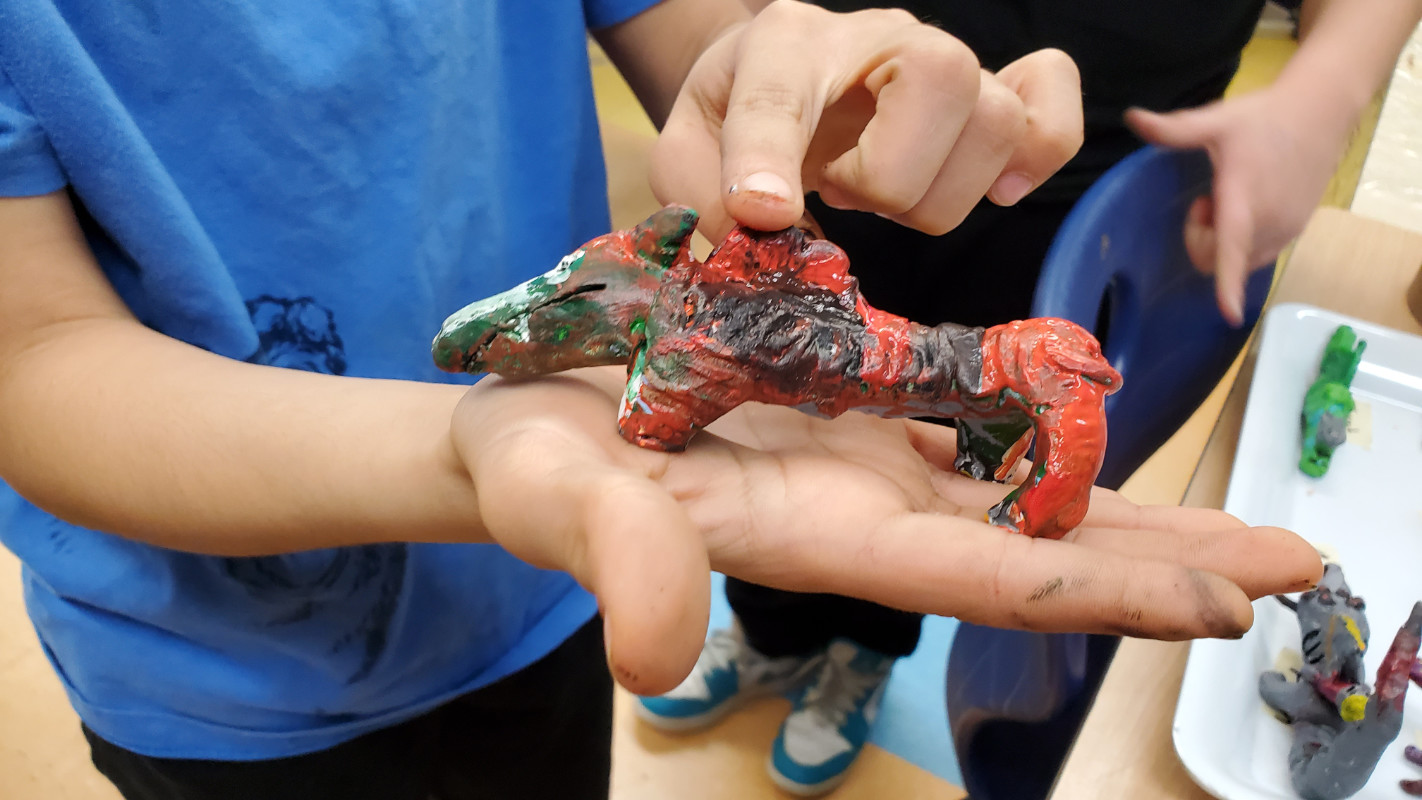 Élève montrant dans ses mains sa figurine d'animal inventé peinte