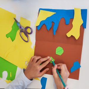 Mains d’un enfant qui dessine sur un morceau de carton vert