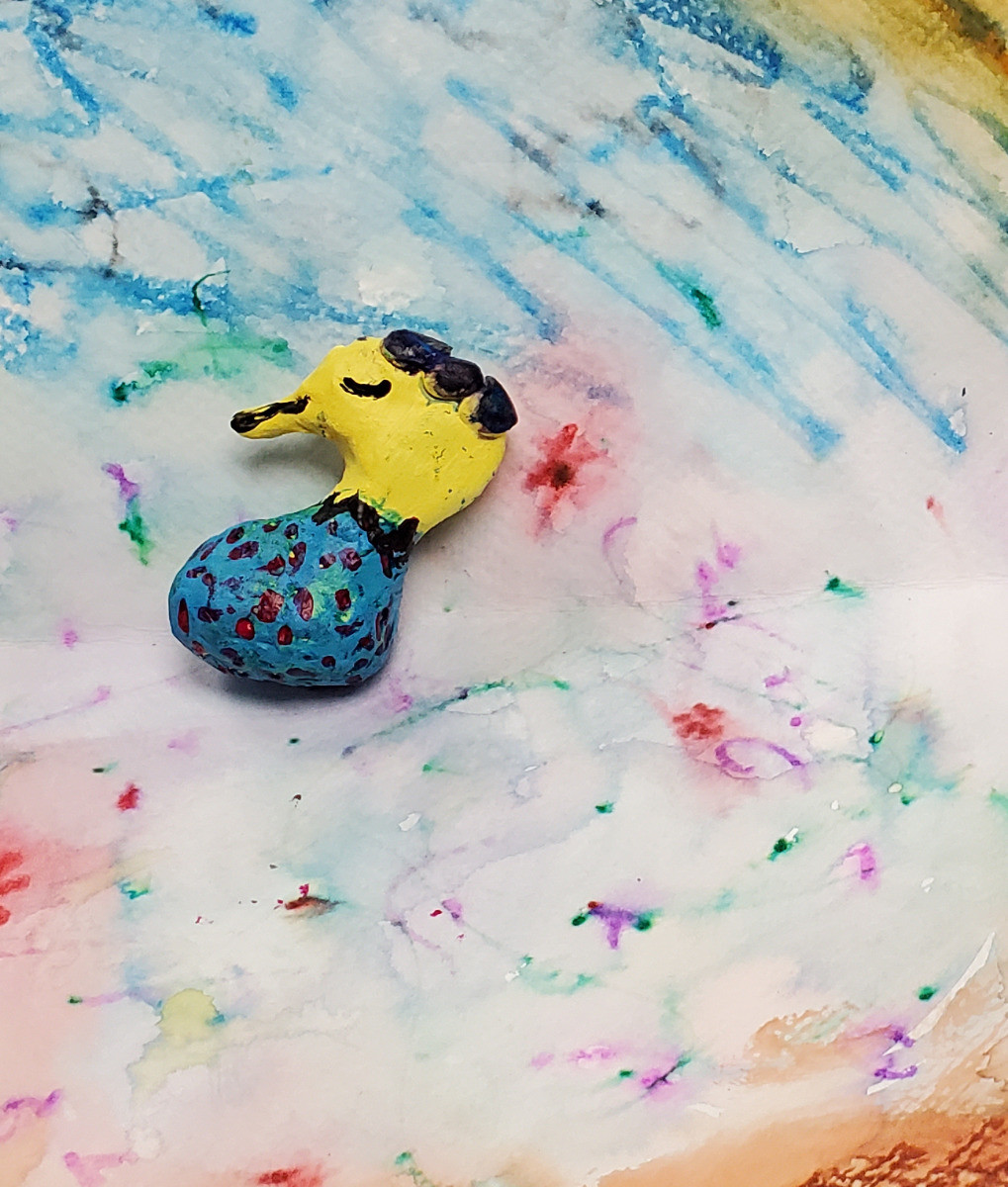 Figurine d’animal inventé avec une tête jaune et un corps bleu sur un arrière-plan multicolore de style aquarelle.