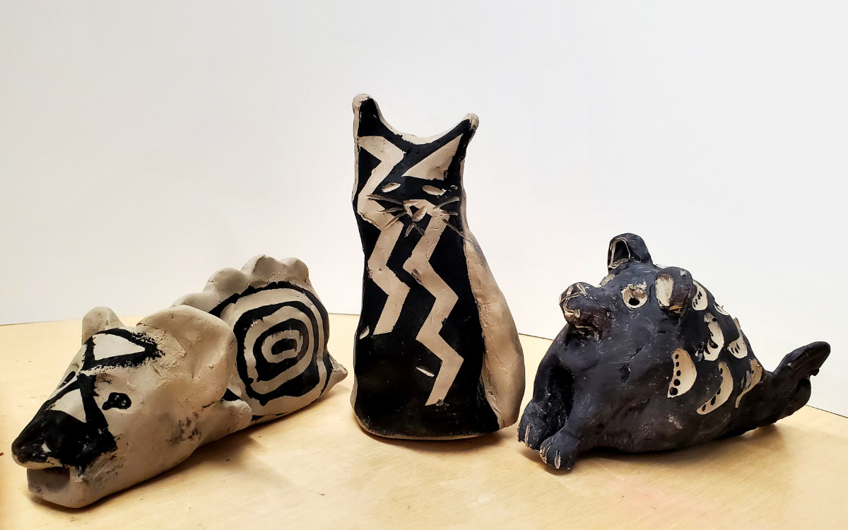 Trois sculptures d’argile représentant des animaux hybrides sur lesquelles il y a des motifs noirs