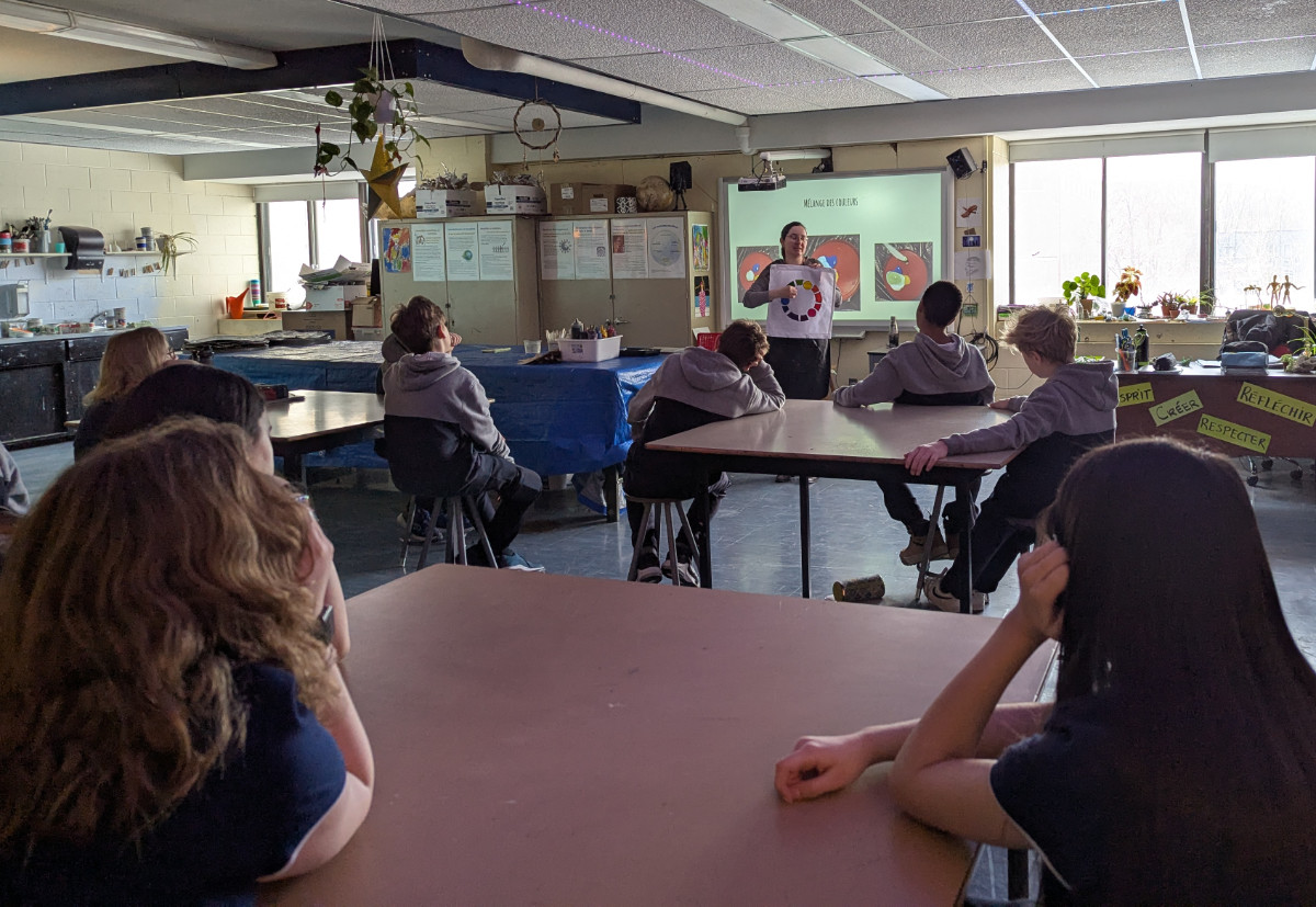 L’artiste Amélie Bissonnette montre un cercle chromatique devant une classe de jeunes du secondaire
